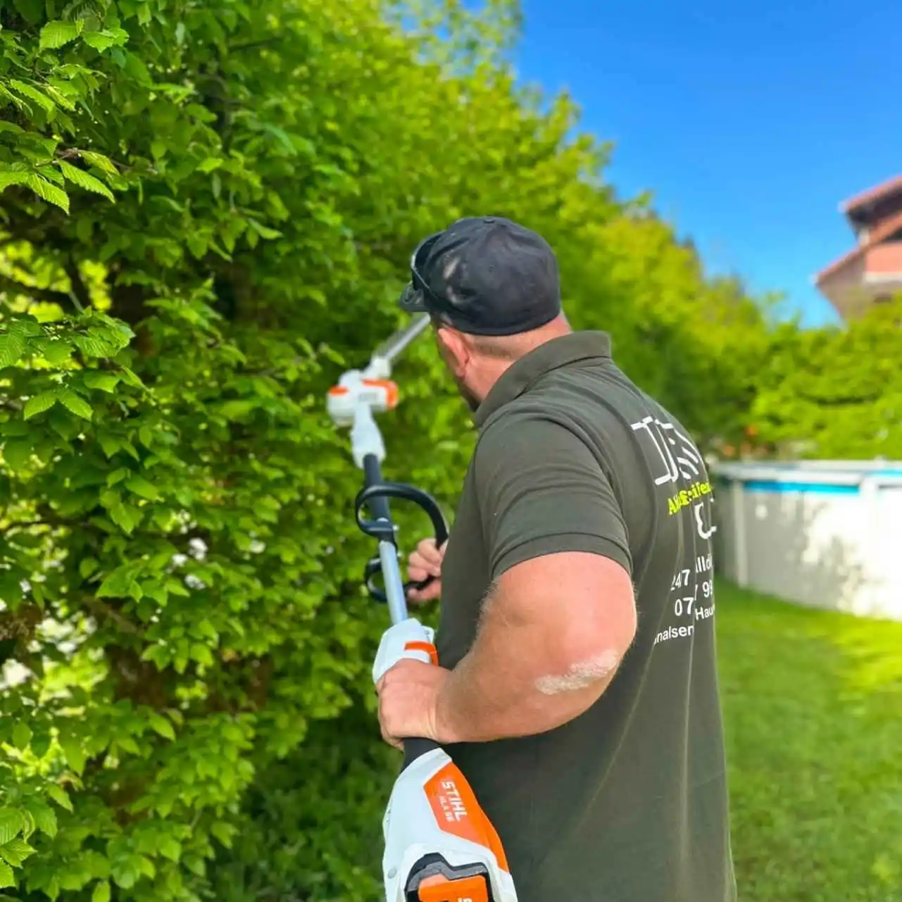 Gartenarbeiter schneidet Hecke mit elektrischem Trimmer