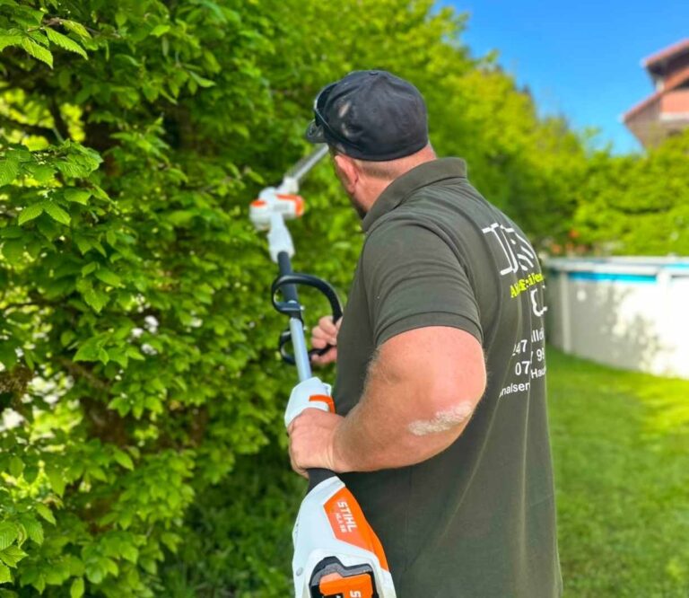 Gartenarbeiter schneidet Hecke mit elektrischem Trimmer