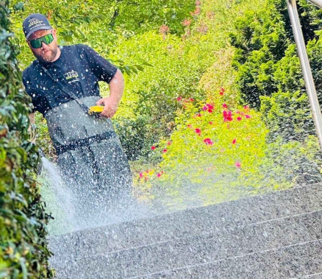 Gartenarbeiter reinigt Boden mit Hochdruckreiniger